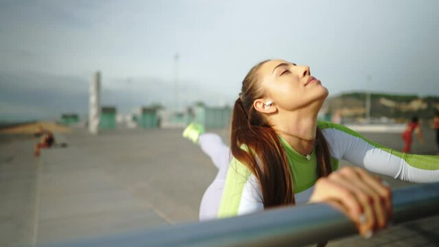 Flexible sportswoman exercising near railing