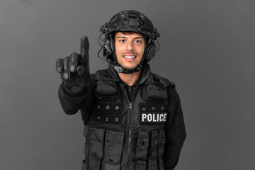 SWAT caucasian man isolated on grey background showing and lifting a finger