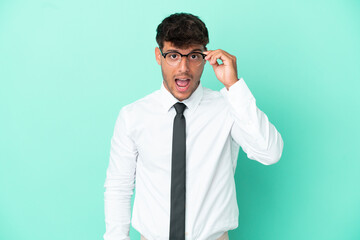 Business caucasian man isolated on blue background with glasses and surprised