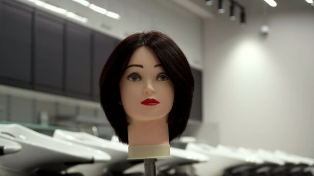 Caucasian woman in black clothes straightens the hair of a mannequin