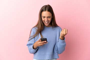 Naklejka premium Young woman over isolated pink background surprised and sending a message