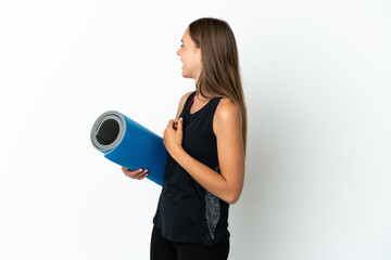 Sport woman going to yoga classes while holding a mat over isolated white background laughing in lateral position