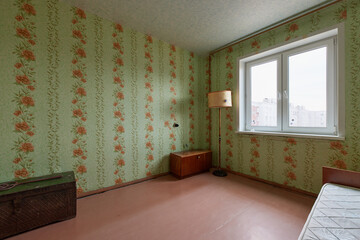 Example of Old Soviet Russian poor interior in Leningrad project House. Aged  sideboard, table, chairs, bed. Shabby floor. Tattered wallpaper on the wall. Apartment of pensioners. Selective focus.