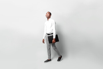 entrepreneur business black man hold laptop go walking look away over gray background.