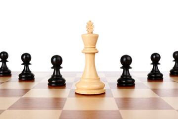 King among black pawns on wooden chess board against white background