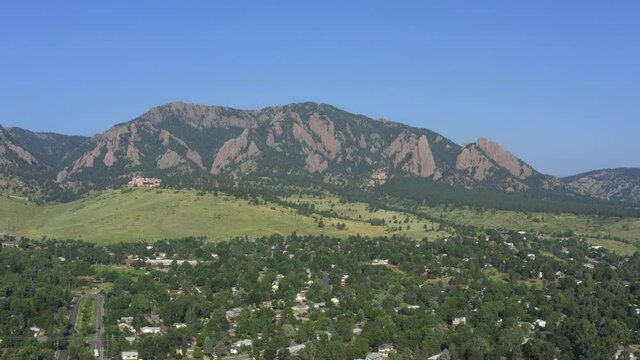 boulder flatirons in colorado during the summer with houses and trees in foreground