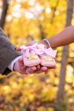 Closeup of couple's hands holding baby girl shoes