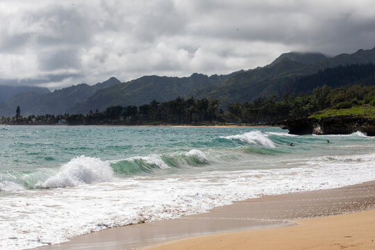 Breaking ocean waves with mountain shoreline in thee background, hawaii