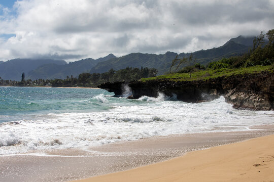 Breaking ocean waves with mountain shoreline in thee background, hawaii