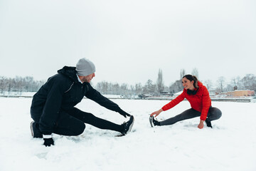 Fototapeta na wymiar Young couple working out together during a snow on a cold winter day