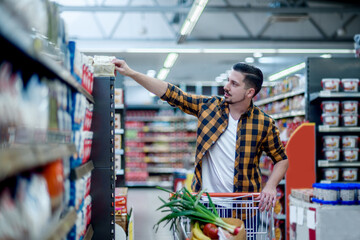 Young handsome man in a supermarket grocery shopping