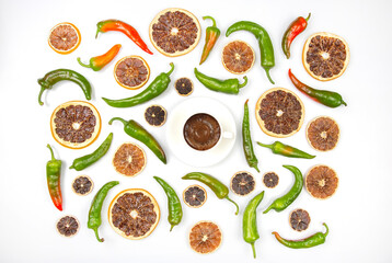 freshly brewed black coffee in a cup on a background of hot green peppers and dried citrus fruit on a white plate. grocery organic flatley