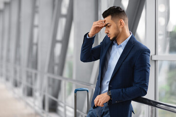 Portrait Of Thoughtful Middle Eastern Businessman Standing With Luggage At Airport Terminal