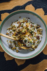greek yogurt with green pistachios and honey in greek key bowl with gold spoon