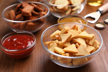 Different crispy rusks and dip sauces on wooden table
