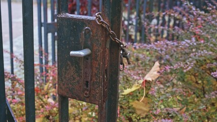 Rusty Metal Property Fence Gate With Damaged Lock and Broken Handle Secured with Iron Chain and Simple Padlock