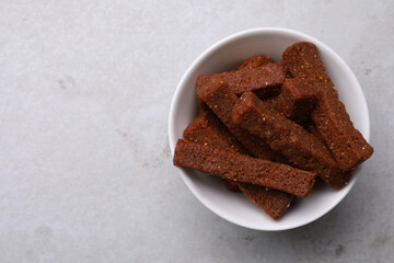 Crispy rusks with bowl on light table, top view. Space for text