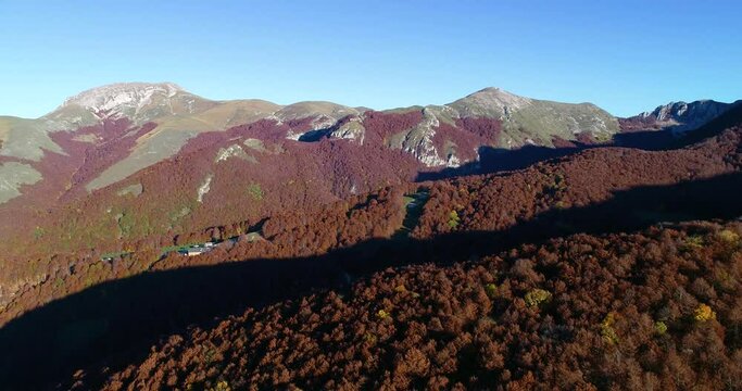 Fall aerial shots over the beech forest at Monte Terminillo, in the central Italy. The beautiful landscape of the rocky mountain and its forest coloured by the warm tones of the fall season.