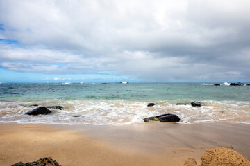 Fototapeta na wymiar ocean, black rocks, waves and blue cloudy sky