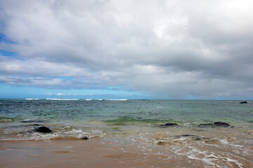 ocean, black rocks, waves and blue cloudy sky