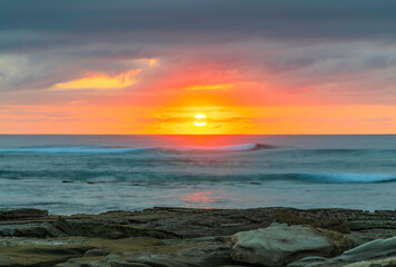 Sunrise seascape with rocky foreground