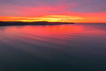 Fototapeta na wymiar One hundred percent colourful cloud covered sunrise over the sea