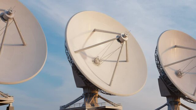 Seamless looping animation of satellite dishes in the blue sky. Technology.