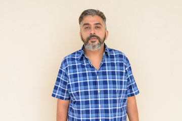 Fototapeta premium Portrait of bearded Indian businessman against plain background
