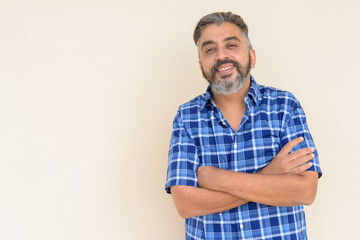 Obraz premium Portrait of bearded Indian businessman smiling against plain background