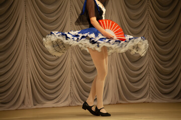 Gypsy dance. A girl in a dress performs on stage. Blue dress in motion.