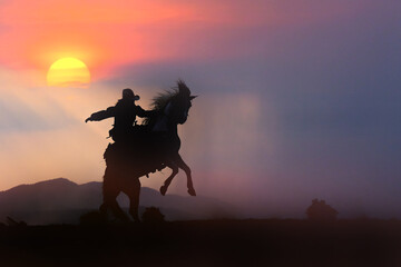 Cowboy silhouette on horseback with mountain view and sunset sky.
