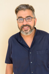 Obraz premium Portrait of bearded Indian businessman smiling against plain background