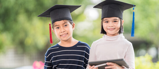 Portrait of cute happy Asian school kid graduate with graduations hat and a diploma isolated on...