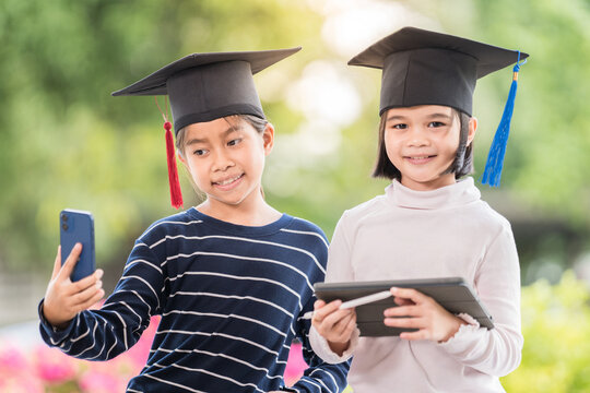 Portrait of cute happy Asian school kid graduate with graduations hat and a diploma isolated on white background. Education Concept Stock Photo