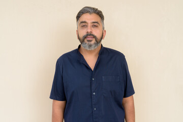 Obraz premium Portrait of bearded Indian businessman against plain background