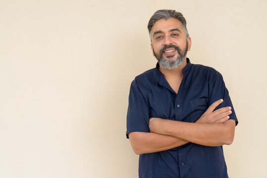 Portrait of bearded Indian businessman against plain background