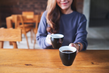 Closeup image of a young woman holding and serving two cups of coffee