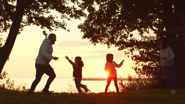 Loving family walks in the countryside during sunset. Mom and Dad hug and play with their son and daughter. The concept of love, parental care and children.