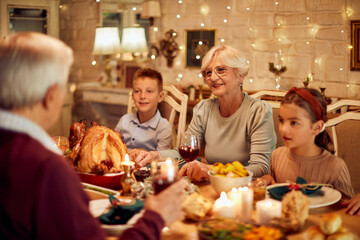 Grandparents and grandchildren talk while having Thanksgiving meal at dining table.