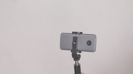 Cell phone mounted on a cell phone tripod, on white background.
