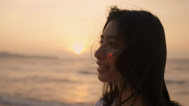 Side view of woman Asian happy smile looking beach at sunset in summer