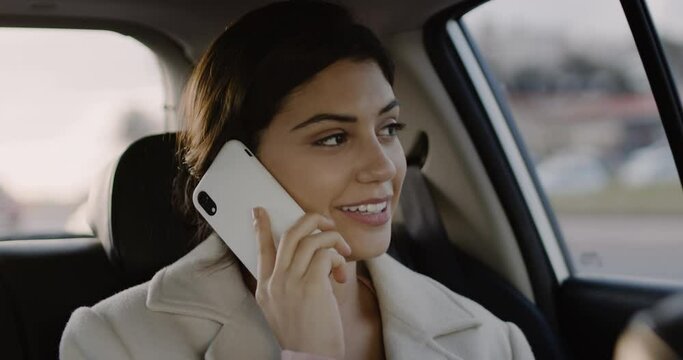 Close Up Slow Motion of Attractive Young Caucasian Woman in Car Using Mobile Phone. Female Brunette on Backseat of Ride Sharing Transportation Talking on Smartphone.
