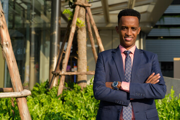 Portrait of successful young African businessman wearing suit and tie with arms crossed