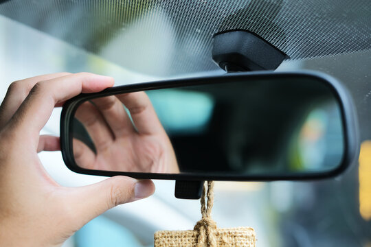 Person hand adjusting the car center rearview mirror