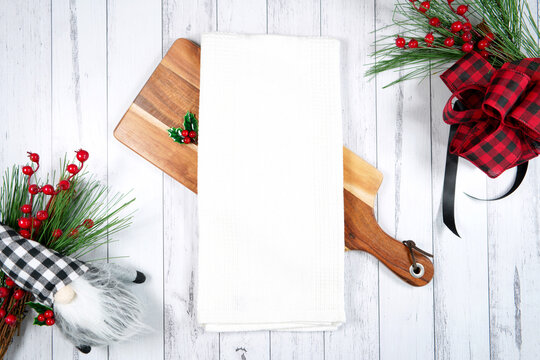 Tea towel kitchen product mockup. Christmas farmhouse theme SVG craft product mockup styled with gift with buffalo plaid bow and farmhouse style gnomes against a white wood background.