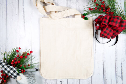 Tote bag product mockup. Christmas farmhouse theme SVG craft product mockup styled with buffalo plaid bow and farmhouse style gnomes against a white wood background.