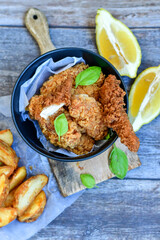  Crispy  deep fried   chicken strips ,onions and шедгес потатоес .Breaded  with cornflakes chicken  breast fillets  with chilly peppers and fresh   basil on wooden rustic background