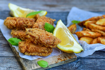  Crispy  deep fried   chicken strips ,onions and шедгес потатоес .Breaded  with cornflakes chicken  breast fillets  with chilly peppers and fresh   basil on wooden rustic background