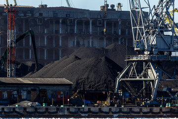 Industrial loading of coal into railway cars. Coal port of the city of Nakhodka. Large excavators are handling coal.