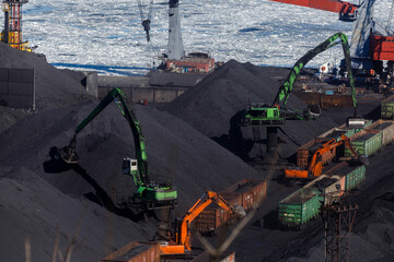 Industrial loading of coal into railway cars. Coal port of the city of Nakhodka. Large excavators...